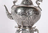 Samovar de metal prateado ricamente cinzelado, ... - Samovar de metal prateado ricamente cinzelado, alça de madeira, pés de garra sobre bola.