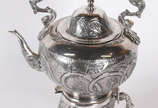 Samovar de metal prateado ricamente cinzelado, ... - Samovar de metal prateado ricamente cinzelado, alça de madeira, pés de garra sobre bola.