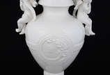 Ânfora em cerâmica branca com detalhes em relev... - Ânfora em cerâmica branca com detalhes em relevo e alças na forma de anjos, procedência italiana. Altura 40 cm.