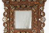Espelho com moldura de madeira ricamente entalh... - Espelho com moldura de madeira ricamente entalhada com aplicações de espelhos ao gosto cuzquenho, encimada por figura de anjo.