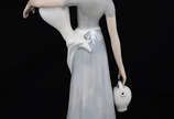 Escultura de porcelana ao gosto Lladro represen... - Escultura de porcelana ao gosto Lladro representando figura feminina com jarros. Altura 35 cm.