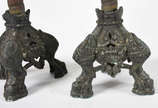 Par de castiçais de metal com bases decoradas c... - Par de castiçais de metal com bases decoradas com figuras de animais estilizados. Metal com desgastes.