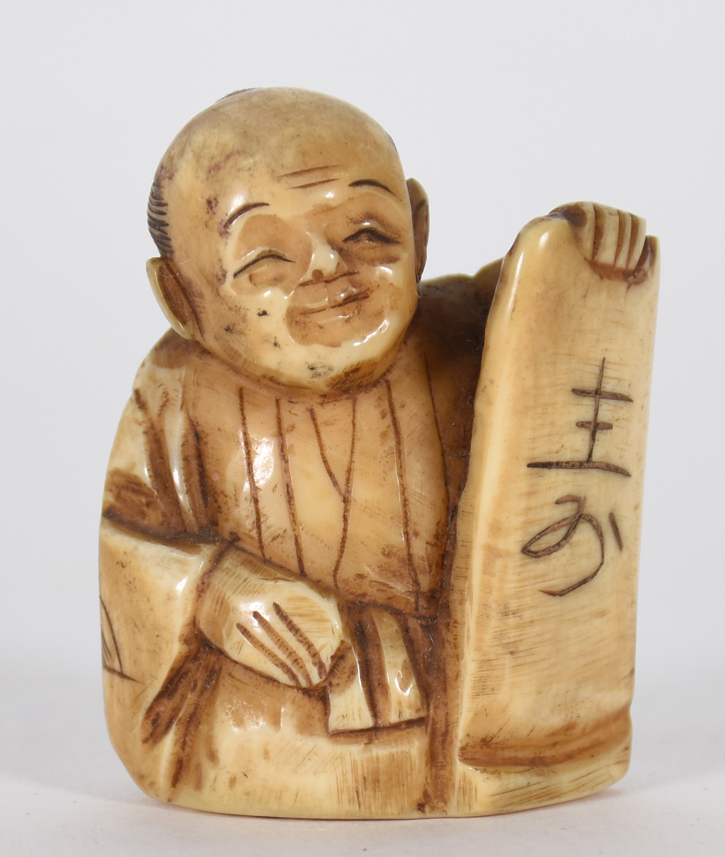 Netsuke de marfim representando figura com placa. - foto 1 de 3