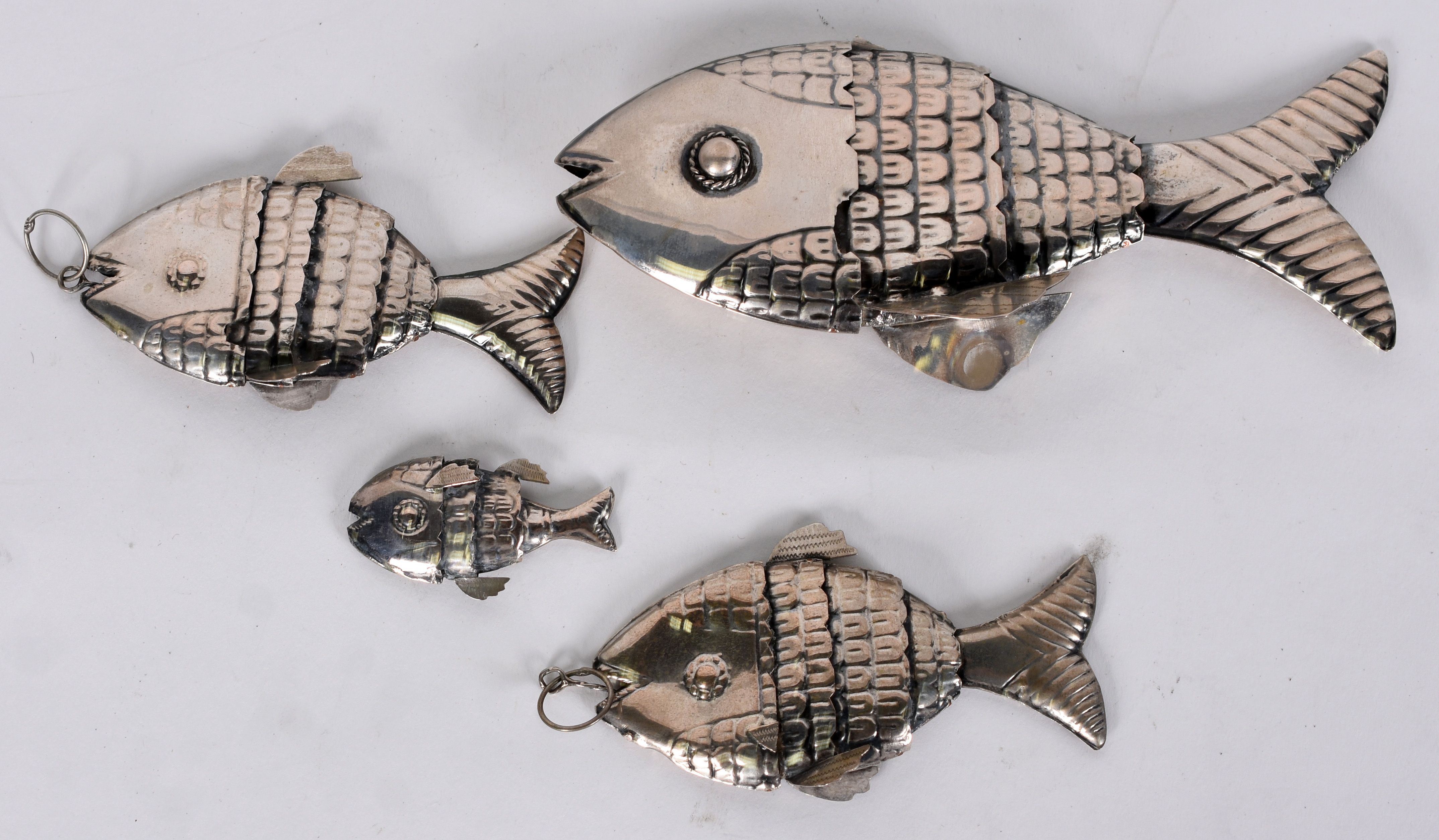Quatro peixes articulados de metal prateado. - foto 1 de 3