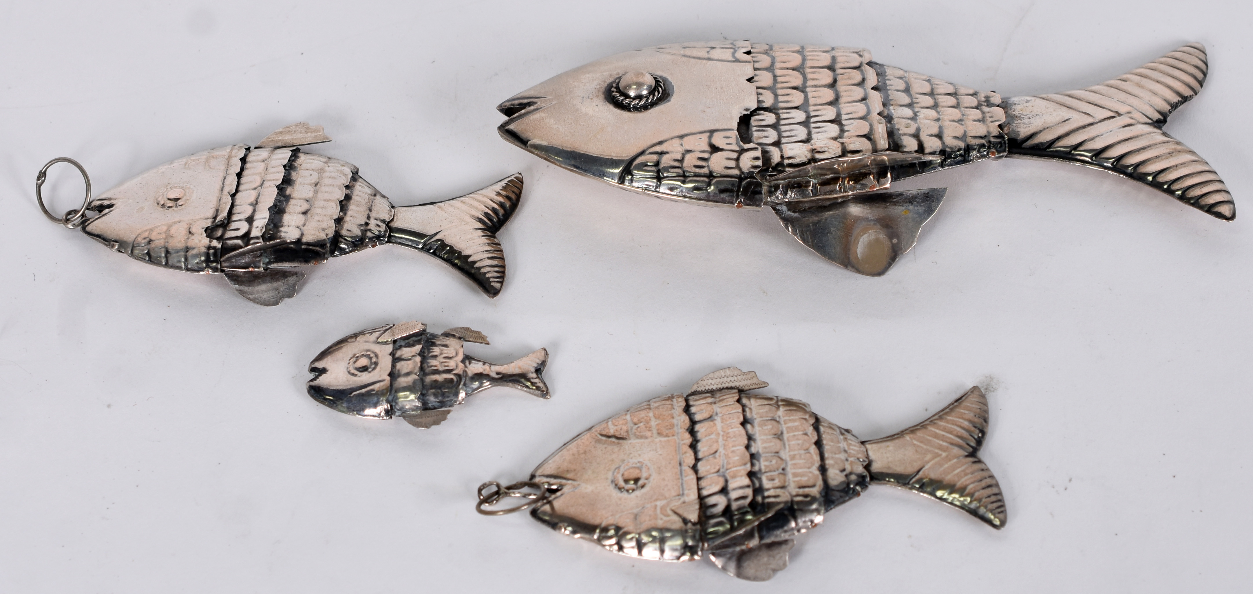 Quatro peixes articulados de metal prateado. - foto 2 de 3