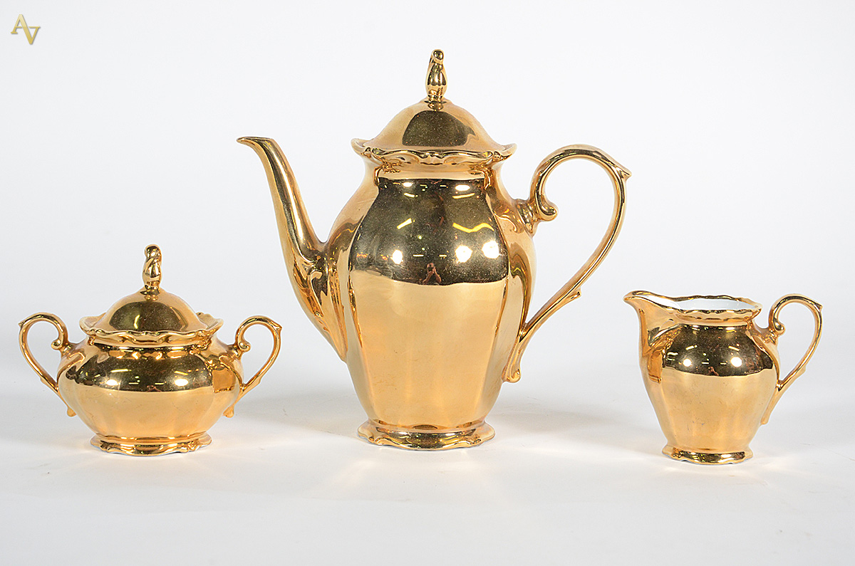Três peças de porcelana dourada para café, sendo: bule, leiteira e...
