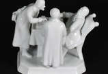 Grupo escultórico de porcelana europeia branca ... - Grupo escultórico de porcelana europeia branca com 3 figuras conversando ao redor da mesa. Marca na base.