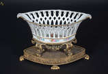 Centro de mesa de porcelana branca, fundo com f... - Centro de mesa de porcelana branca, fundo com flores em policromia, feitio navete com vazados nas laterais, pés de metal dourado. Acompanha base...