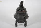 Incensório de bronze chinês com tampa em forma ... - Incensório de bronze chinês com tampa em forma de cão de fó, acompanha peanha de madeira. Altura 44 cm.