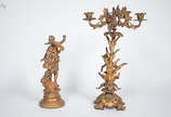 Conjunto com duas peças de petit bronze sendo c... - Conjunto com duas peças de petit bronze sendo candelabro para 4 luzes (altura 52 cm) e escultura representando figura feminina (altura 36 cm).