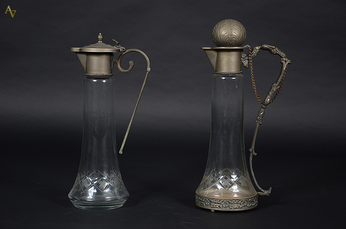 Duas jarras de cristal com tampas de metal, alturas 36 x 38 cm.