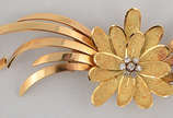 Broche em ouro 18 k no formato de flor e voluta... - Broche em ouro 18 k no formato de flor e volutas, cravejado com 7 brilhantes com total de 0,23 ct. Peso aproximado 20 g.