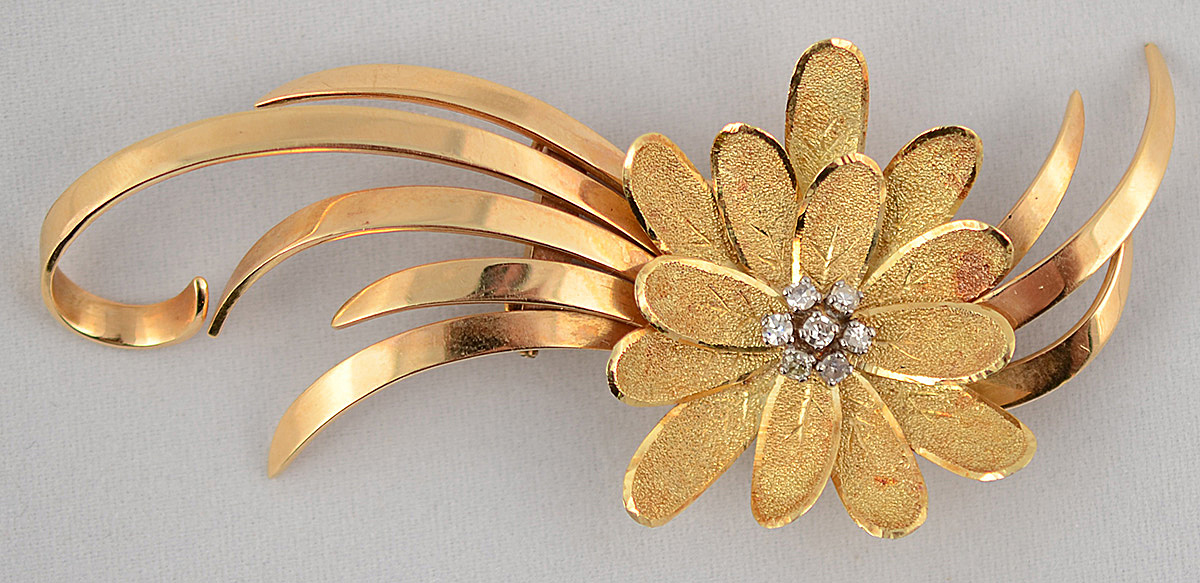 Broche em ouro 18 k no formato de flor e volutas, cravejado com 7...