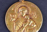 Medalha em ouro 18 k representando Nossa Senhor... - Medalha em ouro 18 k representando Nossa Senhora com Menino Jesus, peso aproximado 3.38 g e medindo 2,5 cm de diâmetro (apresenta mossas no verso).