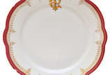 Prato raso em porcelana européia, apresentando ... - Prato raso em porcelana européia, apresentando borda recortada, vermelha com decoração em dourado com o monograma PE. No estado. 