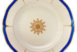 Prato raso em porcelana européia, apresentando ... - Prato raso em porcelana européia, apresentando borda recortada, azul com decoração em dourado com monograma sob coroa de barão. 