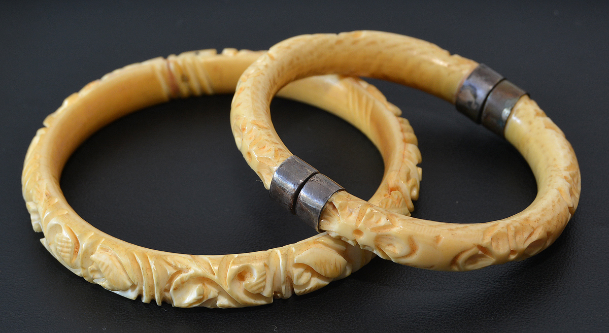 Duas pulseiras em marfim trabalhado, uma delas com fecho em prata...