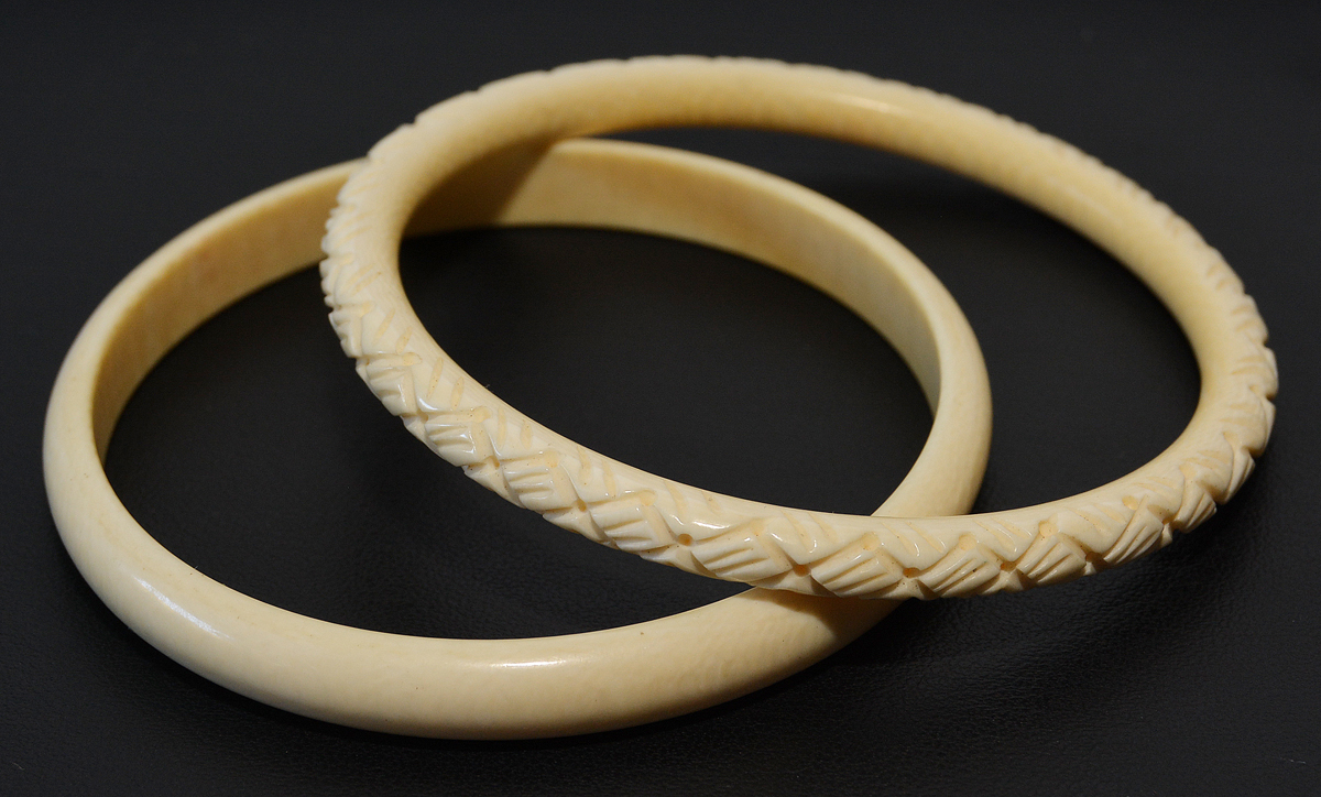 Duas pulseiras em marfim, uma delas esculpida com trabalhos...