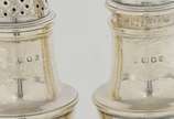Conjunto de saleiro e pimenteiro de formato bal... - Conjunto de saleiro e pimenteiro de formato balaustre em prata inglesa lisa. Tampas vazadas com pegas em pião. <br>Bases circulares. Contrastes ...