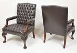 Par de poltronas inglesas com estofamento em ca... - Par de poltronas inglesas com estofamento em capitonê em couro preto com estrutura em madeira nobre entalhada, pés frontais terminados em forma ...