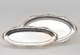 Conjunto com 2 travessas ovais em metal pratead... - Conjunto com 2 travessas ovais em metal prateado lavrado, bordas decorada e onduladas com suaves volutas filtradas. Marca do fabricante.