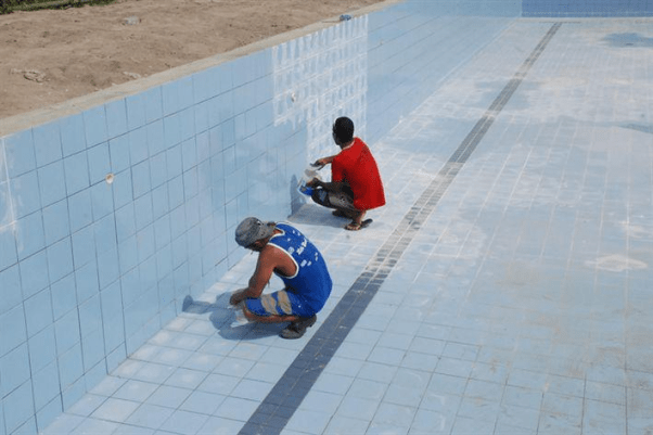 Foto de homens aplicando rejunte para piscina