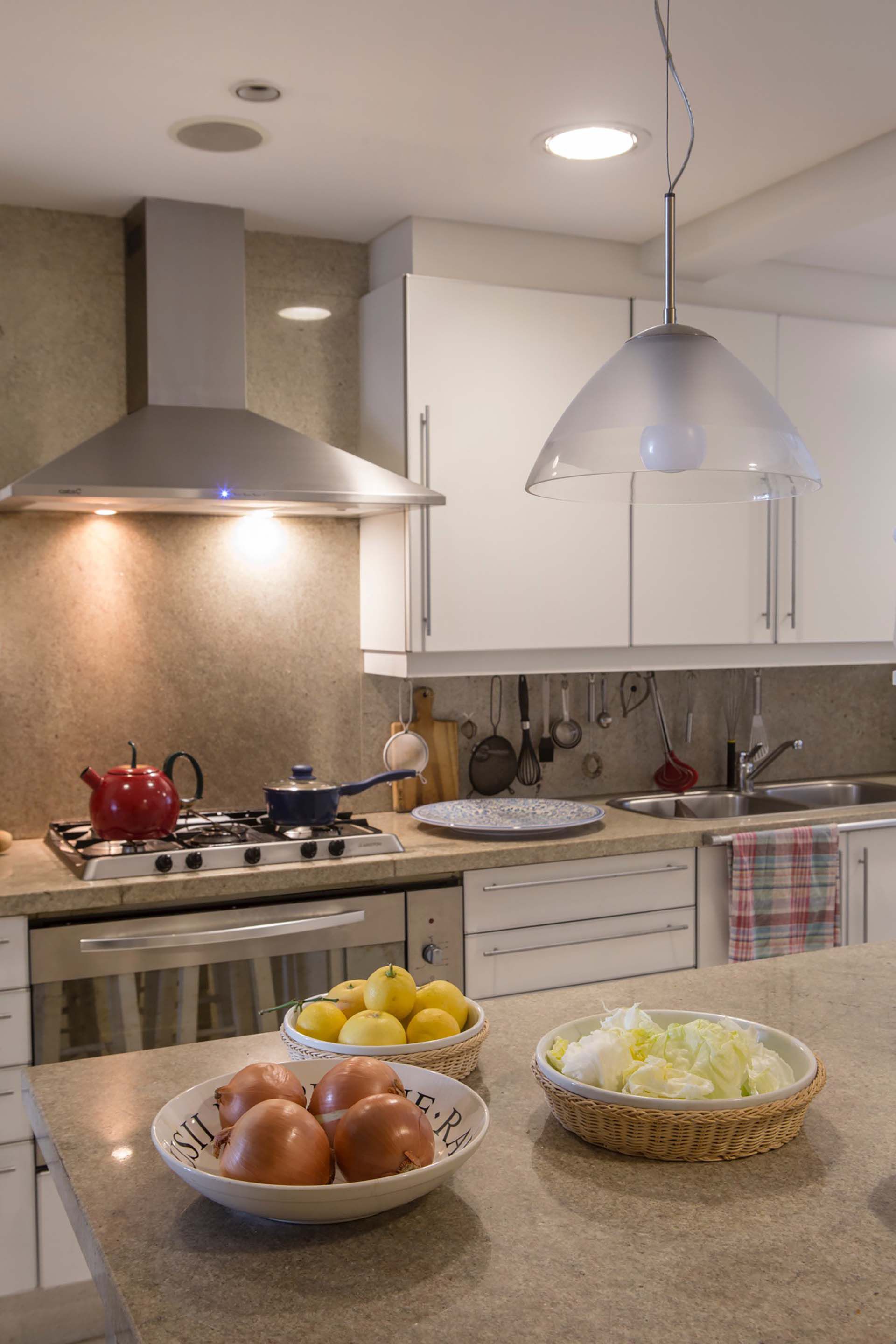 Muebles laqueados en blanco y grandes placas de granito sin pulir para la moderna cocina.