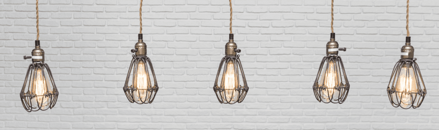 Várias luminárias suspensas com lâmpadas de filamento acesas.