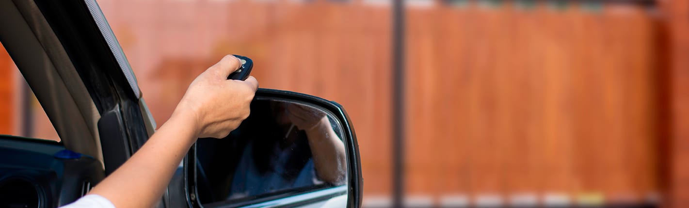 Pessoa usando um controle remoto para abrir automaticamente o portão sem sair do veículo