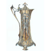<p>Elegante jarra de metal prateado, com a marca alemã WMFB (Württembergische Metallwarenfabrik), em estilo Art Nouveau, decorada com motivos florais e orgânicos em relevo, alça e tampa estilizadas, apoiada sobre quatro pés. Medindo 31 cm de altura.</p>