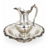 <p>Conjunto de lavabo composto por jarra e bacia de metal prateado (silver plate), manufatura Reed & Barton, modelo 560, bordas ricamente decoradas em relevo - diâm 48 cm e 33 cm alt - Produção americana, séc XIX/XX</p>