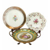 <p>Lote com três peças em porcelana decorada, com douração, composto por grande prato com decoração floral (35 cm), fruteira em suporte e varanda de metal trabalhado com cena romântica (30 cm) e travessa de bordas recortadas com decoração floral (30 cm) - No estado</p>