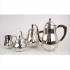 <p>WMF, Conjunto de chá e café de metal espessurado à prata, decorado com repuxados e corpos facetados, contém 02 bules, 01 açucareiro e 01 cremeira, cabos e pegas superiores de madeira nobre. Alt. 24 x 24 x 13cm (maior) e 11 x 14 x 11cm. (menor). Alemanha, séc. XX</p>
