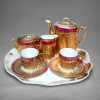 Antigo Tête-à-Tête em Porcelana - Douração e Faixa Grená - c. 1920 - 6 Peças<br /><br />Antigo e raro serviço de chá / café tête-à-tête para 2 pessoas, porcelana europeia circa 1920 - conjunto tête-à-tête constando de 6 peças.<br /><br />Composição:<br /><br />01 bandeja oval recortada (25 x 21 x 11 cm) com douração e resquícios de uso<br />01 bule / chocolatière com tampa e pega laçada<br />01 açucareiro com tampa 2 alças (pegador / puxador no estado)<br />02 xícaras de café com 02 pires - caneladas com faixa grená / rosa profundo e rica douração em filetes, perolados e raios estrelados<br />Decoração primorosa em ouro pesado canelado cobrindo quase todo o corpo, faixa em grená com motivos dourados de folhagens estilizadas / fleurs-de-lis, pires com decoração radiante em raios dourados.<br /><br />Porcelana fina, esmaltada em branco, canelura em relevo vertical no corpo e tampa estriada em gomos.<br /><br />Medidas bandeja: 25 x 21 x 11 cm