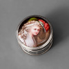 <p>Raro WMF - GERMANY - W&uuml;rttembergische Metallwarenfabrik - Raro Porta Joias / Bomboniere em Metal Prateado com Tampa em Porcelana Policromada Figurando Dama da Nobreza - Orla Trabalhada em Fest&otilde;es - Modelo 27055a Reproduzido no Livro WMF Musterbuch 1920, P&aacute;gina 188 - Marca Referente ao Per&iacute;odo 1910 - Medidas 5,5 x 8 x 8 cm. Pe&ccedil;a: Raro Porta Joias / Joaillier / Jewel Casket - WMF - Modelo 27055a - Alemanha - c. 1910 - Reproduzido no cat&aacute;logo hist&oacute;rico WMF Musterbuch 1920, p&aacute;gina 188. Corpo em metal branco prateado (Britannia metal) com banho de prata, formato circular baixo com 8 cm de di&acirc;metro, base com orla trabalhada em fest&otilde;es / grinaldas em relevo estilo Jugendstil tardio, tampa plana em porcelana policromada com pintura &agrave; m&atilde;o de dama da nobreza em traje Belle &Eacute;poque com chap&eacute;u de plumas e fundo paisagem, borda da tampa com filete dourado e acabamento espelhado. Interior com banho original preservado. Marca: WMF - Marca de avestruz dentro de losango com WMF e GERMANY - referente ao per&iacute;odo 1903-1914, modelo com numera&ccedil;&atilde;o 27055a gravada no fundo. Medidas: 5,5 cm altura x 8 x 8 cm di&acirc;metro Material: Metal prateado e porcelana policromada pintada &agrave; m&atilde;o T&eacute;cnica: Fundi&ccedil;&atilde;o, pratea&ccedil;&atilde;o e pintura em porcelana Origem: Alemanha - Geislingen - WMF - c. 1910 Refer&ecirc;ncia Bibliogr&aacute;fica: WMF Musterbuch 1920, p. 188 - modelo 27055a Estado: Bom, com patina nobre, micro-riscos no prateado compat&iacute;veis com idade, porcelana sem lascas ou restauros, pintura com cores vivas preservadas CONTEXTO: A W&uuml;rttembergische Metallwarenfabrik foi a maior f&aacute;brica de metais decorativos da Alemanha entre 1853 e 1980, famosa pelos objetos em estilo Jugendstil / Art Nouveau e historicista com tampas em vidro, porcelana e esmalte. Os porta joias com tampa de porcelana policromada com figuras galantes s&atilde;o da fase mais refinada da produ&ccedil;&atilde;o WMF, entre 1905-1915, destinados &agrave; exporta&ccedil;&atilde;o para o mercado de luxo, hoje altamente colecion&aacute;veis e catalogados no Musterbuch de 1920. Pe&ccedil;a de colecionismo WMF, porta joias Belle &Eacute;poque, caixa com porcelana pintada, Jugendstil, refer&ecirc;ncia em livro.</p>