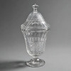 <p>Compoteira alta com tampa e p&eacute; - em vidro prensado transparente incolor - padr&atilde;o Bico-de-Jaca / Abacaxi - tamb&eacute;m chamado Padr&atilde;o Diamante / Diamond Point / Sawtooth - anos 1930 - Art D&eacute;co. Bojo em forma de urna / tulipa evasada com base em pedestal circular com estrela de 8 pontas no fundo - corpo com 3 registros: borda superior lisa com friso ondulado, faixa central vertical canelada em gomos, e faixa inferior em losangos / bico-de-jaca em relevo piramidal denso - tampa em c&uacute;pula com mesmo padr&atilde;o, arrematada por pombo / pega em forma de diamante lapidado facetado - lapida&ccedil;&atilde;o brilhante. Vidro espesso, pesado, cristalino. T&eacute;cnica: Vidro prensado em molde - pressed glass - com acabamento de lapida&ccedil;&atilde;o manual no pombo. Medidas: 32 cm altura total com tampa x 15 cm di&acirc;metro borda x 15 cm di&acirc;metro base x 11 cm profundidade bojo - Tampa: 12 cm altura x 14,5 cm di&acirc;metro Material: Vidro prensado transparente - incolor Modelo: Bico-de-Jaca - Diamond - Pineapple - Sawtooth - Compoteira de P&eacute; Origem: Brasil - Cristais Camb&eacute; / Cisne / Wheaton / E.U.A. - Indiana Glass - Anos 1930 - Art D&eacute;co Estado: Excelente - sem lascas, sem trincas, sem riscos - tampa encaixa perfeito - brilho intenso CONTEXTO: O padr&atilde;o bico-de-jaca foi o padr&atilde;o mais popular de vidro prensado no Brasil entre 1920-1950, usado em compoteiras, a&ccedil;ucareiros e bomboni&egrave;res para doces, balas e bombons. As compoteiras altas de p&eacute; com tampa pombo diamante eram chamadas de bomboni&egrave;re de noiva e faziam parte do enxoval das casas da elite paulista e carioca na era Art D&eacute;co. O termo bico-de-jaca refere-se ao relevo pontiagudo que imita a casca da fruta jaca, criado para refratar a luz como cristal lapidado a pre&ccedil;o popular. Pe&ccedil;a para cole&ccedil;&atilde;o de vidro prensado, compoteira bico-de-jaca, bomboni&egrave;re anos 30, cristais antigos.</p>