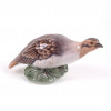 <p>Royal Copenhagen, escultura em porcelana dinamarquesa com rico trabalho em esmalte, representando figura de “Perdiz” (Partridge). 10 cm alt x 21 cm larg.</p>