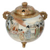 <p>Queimador de incenso Hododa. Japãó, Era Meiji (1868–1912), c. 1880–1910. Queimador de incenso de porcelana policromada e dourada no padrão Satsuma. Corpo bojundo trípode, inteiramente decorado com paisagens, gueichas e cenas do cotidiano; dois pegas verticais diametralmente opostos e tampa com três furos codiformes. Ideogramas japonês no reverso do fundo, simbolo auspicioso de oferenda; 15,8 cm de altura total. Um dos pés, apresenta colagem ou fio de cabelo em seu entorno.</p>