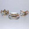 <p>Xícara, Leiteira e Açucareiro de Porcelana - Japão, século XX. Conjunto de três peças, com seus respectivos pires, de fina porcelana japonesa, dita casca de ovo, ornadas com pintura policromada de paisagem e cenas do cotidiano. Xícara, cremeira e açucareiro com tampa. No reverso das bases ideograma em vermelho.</p>