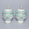 <p>Par de cremeiras de porcelana, corpo com alça lateral decorado com friso verde água entre filetes dourados e tampa com pega no formato de fruto, monograma BJJ entrelaçado, marca F. Domartin Paris; 10 cm de altura. França, séc. XIX. Apresentam bicados.</p>