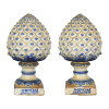 <p>Par de Pinhas de Fainça. Portugal, Século XIX. Par de pinhas de faiança esmaltada com detalhes em azul, sobre fundo creme. Na base quadrada, de 16 cm x 15 cm, marcas da fábrica de Devezas J P Valente. Normalmente, por ficarem expostas em áreas externas, apresentam marcas de ação do tempo, degastes no esmalte, restauros e colagens; 51,5 cm de alturas de alturas totais.</p>