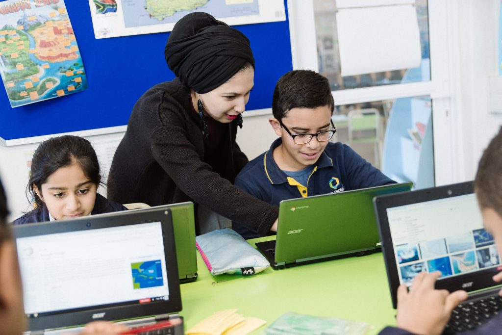 Teacher pointing out information to a student on a laptop