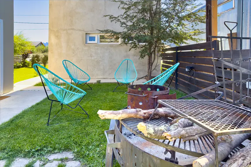 Acceso a patio parquizado con parrilla