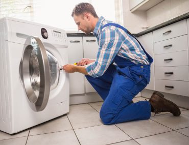 Homem realizando conserto de máquina de lavar